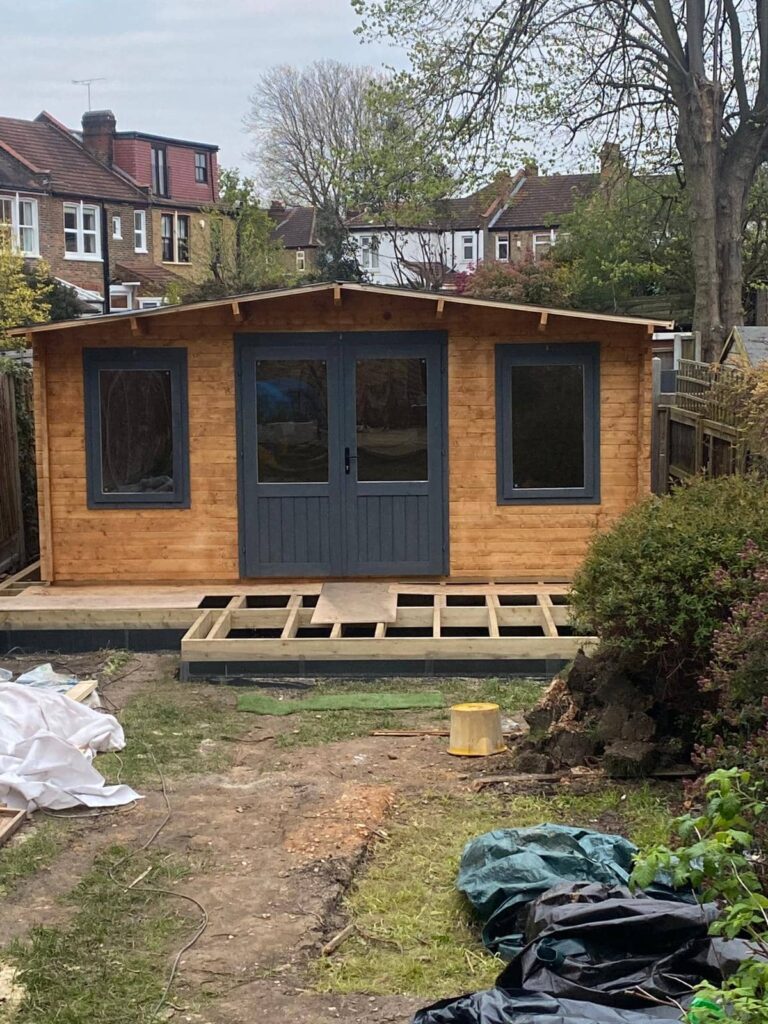 Finished garden cabin with incomplete timber decking surrounding it.